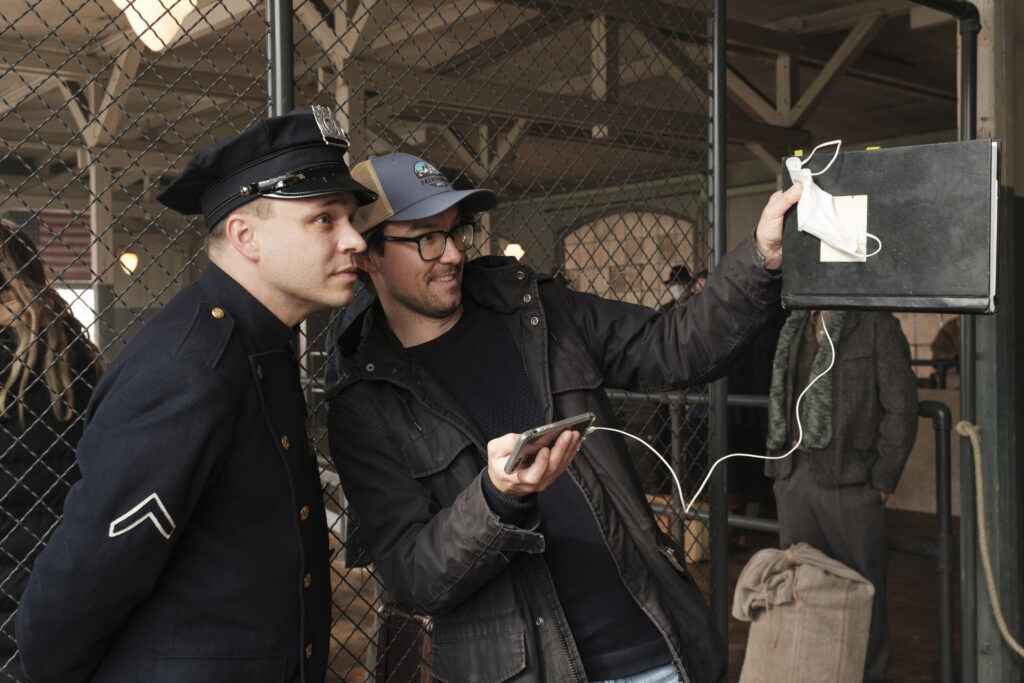 Jonas Baeck in einem Polizeikostüm und der Regisseur an einem Filmset